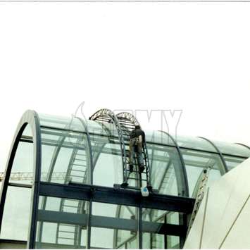 Black Building Maintenance Unit used on a glass rounded roof. Glass rounded roof BMU - Building Maintenance Unit